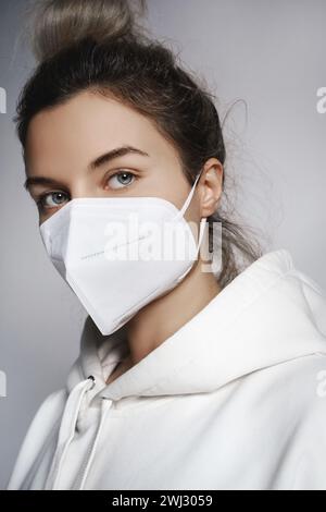 Young woman wearing white hoodie and ffp2 respirator mask Stock Photo