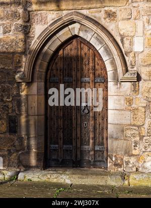 Old wooden door with knocker and key hole surrounded by stonework at Hexham Abbey, Northumbeland, UK Stock Photo