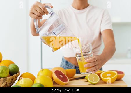 Woman pouring freshly squeezed homemade orange juice into the glass Stock Photo