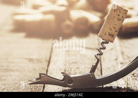 Vintage corkscrew and wine cork on wooden surface Stock Photo