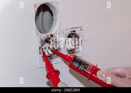 Hand of Electrician testing for electricity with a voltage tester. Electrician checking wall socket Stock Photo