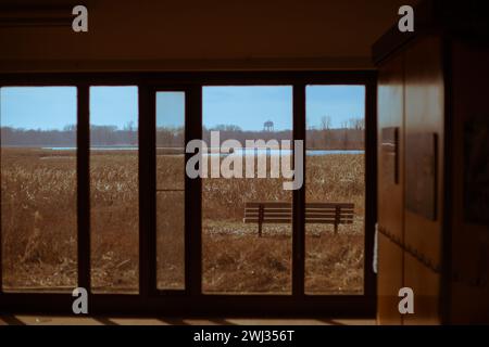 A solitary bench positioned in a vacant hallway, flanked by a pair of transparent glass doors Stock Photo