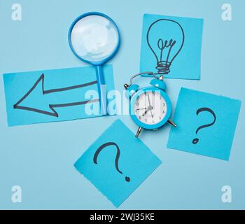 Drawn light bulbs on sheets of paper and a plastic magnifying glass, the concept of searching for new ideas Stock Photo