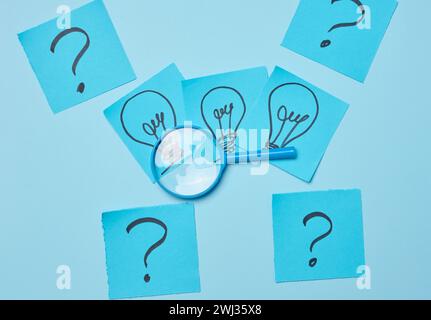 Drawn light bulbs on sheets of paper and a plastic magnifying glass, the concept of searching for new ideas Stock Photo