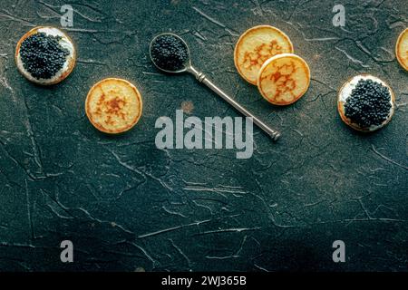 Blinis with black caviar and cream cheese, shot from above on black Stock Photo