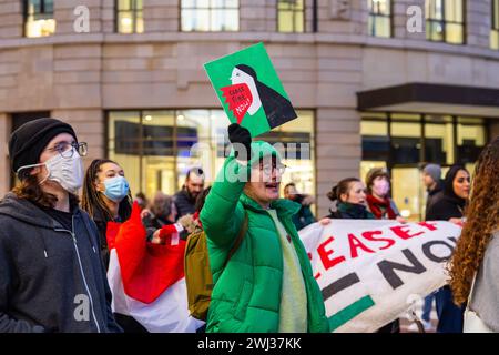Leeds, UK. 12 FEB, 2024. Protestor holds a 'ceasefire now' placard  amongst other demonstrators gathered outside Leeds train station. Credit Milo Chandler/Alamy Live News Stock Photo