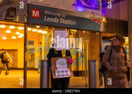 Leeds, UK. 12 FEB, 2024. Protestor holds 'no more aparthied no more genocide banner' outside the entryway to Leeds train station. Credit Milo Chandler/Alamy Live News. Credit Milo Chandler/Alamy Live News Stock Photo