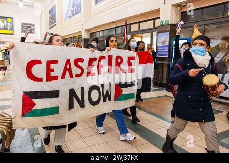 Leeds, UK. 12 FEB, 2024. Pro Palestine demonstrators march through Leeds Station waving flags and banners. A large banner reads 'Ceasefire Now' Credit Milo Chandler/Alamy Live News Stock Photo