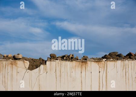Clay damaged collapsing wall against blue cloudy sky. Deserted places. Copy space Stock Photo