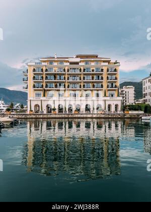 Regent Hotel is reflected in the sea against the backdrop of the mountains. Porto, Montenegro Stock Photo