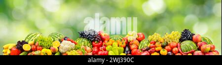 Fresh healthy vegetables, fruits, berries on green blurred background. Stock Photo