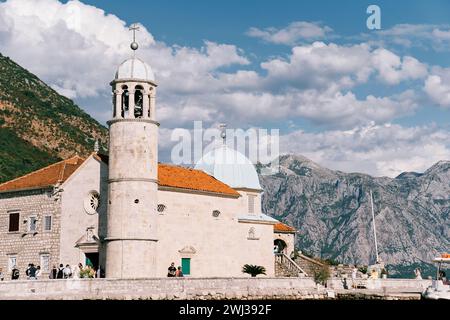Tourists stand at the Church of Our Lady of the Rocks on an island in the Bay of Kotor. Montenegro Stock Photo