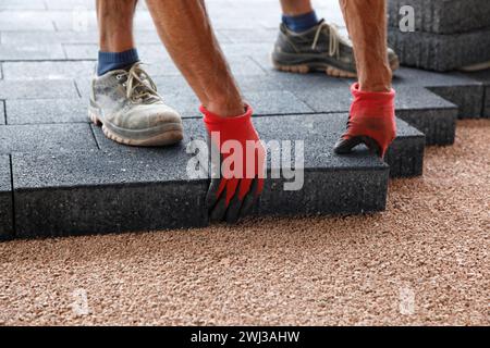 Hands of a worker laying paving, big concrete paver blocks. Laying concrete paving slabs. Builder Stock Photo