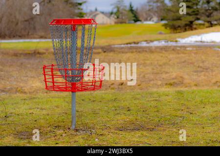 Red disc golf goal, net, pole hole, entrapment basket on a raw winter day. Stock Photo