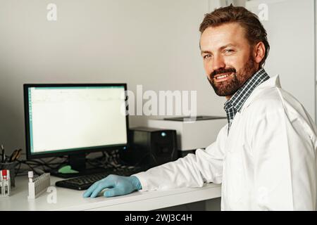 Smiling medical scientist in uniform working on personal computer in research laboratory Stock Photo