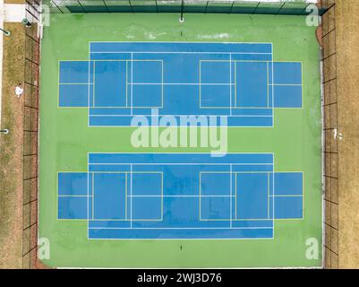 Aerial photo of unusually painted outdoor blue tennis courts with yellow pickleball lines and green out of bounds area. Stock Photo