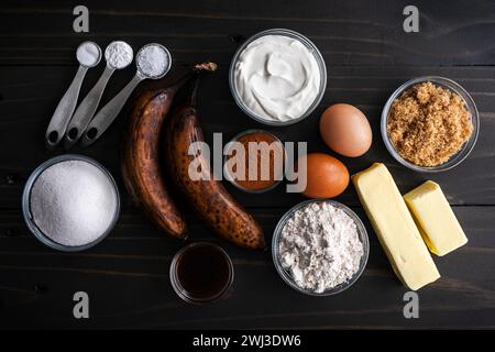 Banana Cinnamon Muffin Ingredients on a Dark Wooden Table: Over-ripe bananas, ground cinnamon, and other breakfast muffin ingredients on a table Stock Photo