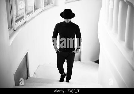 Stylish man in black with hat looking down. Stock Photo