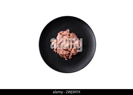 Delicious canned tuna meat on a black ceramic plate on a dark concrete background Stock Photo