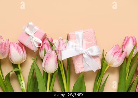 Pink tulips with gift boxes on beige background Stock Photo