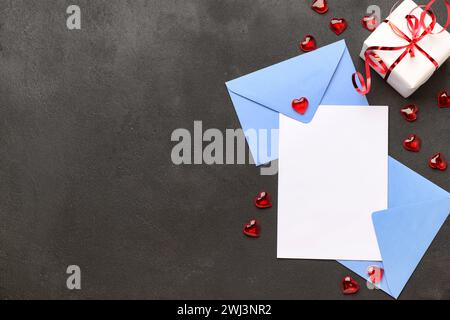 Envelopes with blank card, gift box and hearts on black grunge background. Valentine's Day celebration Stock Photo