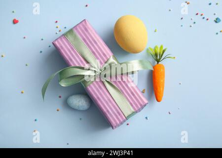 Easter eggs with carrot and gift box on blue background Stock Photo