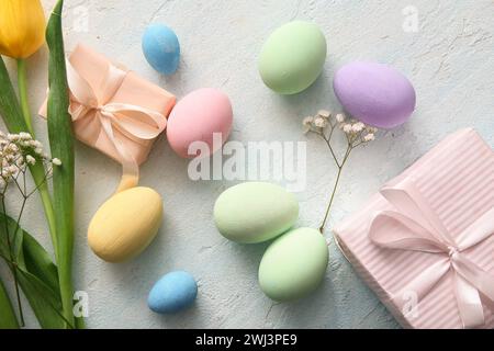 Painted Easter eggs with flowers and gift boxes on blue grunge background Stock Photo