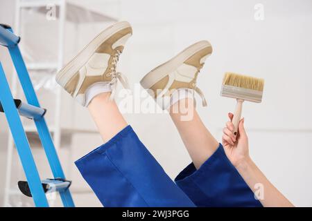 Female painter with brush falling down from stepladder in room, closeup. Trauma concept Stock Photo