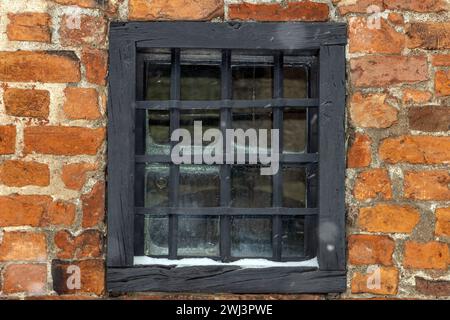 A window protected by a grill on the brick facade of a building Stock Photo