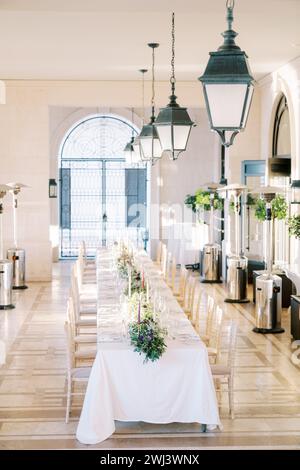 Set long festive table with candles and bouquets of flowers in the large hall of the hotel Stock Photo