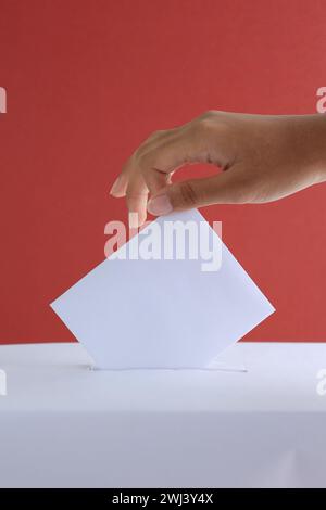 Female Hand Voting Near Ballot Box on Red Background, Concept Pemilu General Election Stock Photo