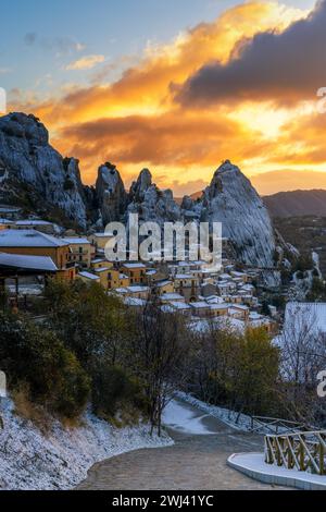 Road leads down into Castlemzzano village in winter with a colourful sunrise sky above Stock Photo