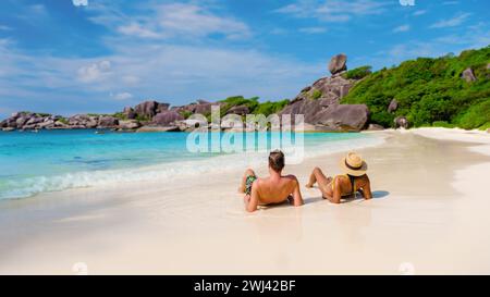 Asian women and white men relaxing on the beach in the sun at the Similan Islands Thailand Stock Photo