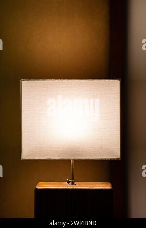 Glowing lamp on nightstand In the evening. Stock Photo