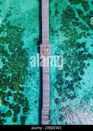 Couple of men and woman lying down on a wooden pier in the oceanof Koh Kham Trat Thailand Stock Photo