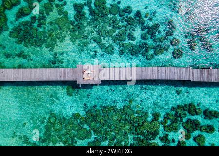 Couple of men and woman lying down on a wooden pier in the oceanof Koh Kham Trat Thailand Stock Photo