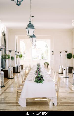 Long laid festive table with candles and bouquets in a large room Stock Photo