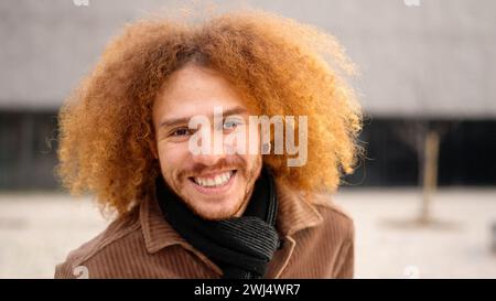 Young man with curly hair smiling at camera Stock Photo