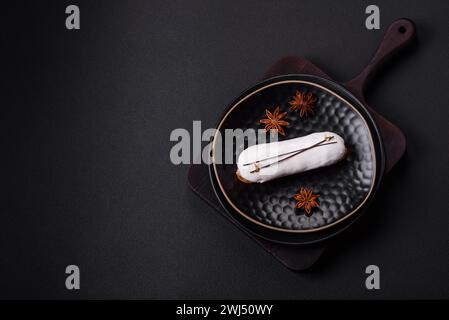 Delicious fresh profiterole or eclair with chocolate on a black ceramic plate Stock Photo