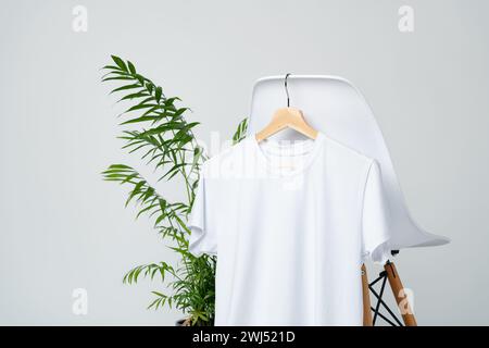 White blank t-shirt hanging on chair in empty room Stock Photo