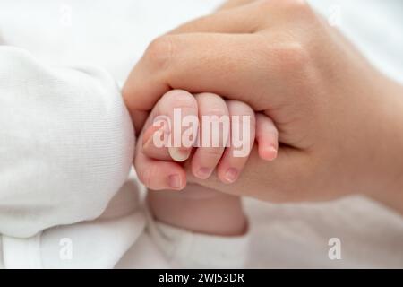 Newborn's delicate grip on mother's thumb exudes trust. Concept of pure maternal connection Stock Photo