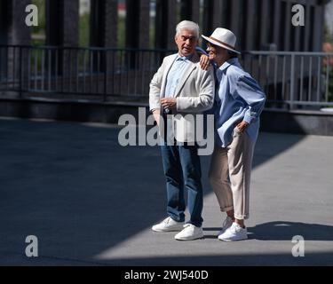 Stylish mature couple. Gray-haired man and woman holding hands while walking around the city.  Stock Photo