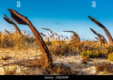 Rusty old anchors on the beach at the Anchor Cemetary graveyard at Praia do Barril beach, in Tavira, Algarve, Portugal Stock Photo