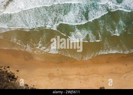 Portugal beach in Sagres, Algarve. Surfers on Atlantic Ocean waves and sandy beach. Aerial drone top down view Stock Photo