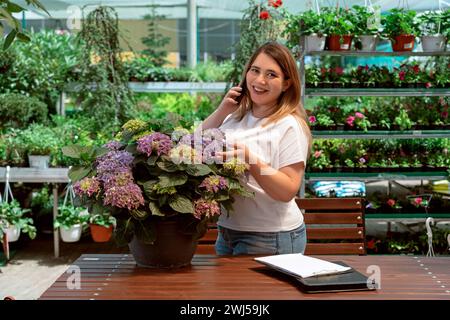 Portrait of garden center manager working with flowers and talking on phone Stock Photo