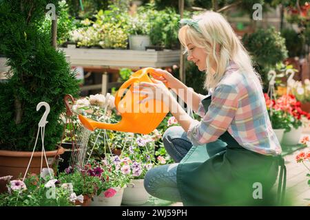 Young woman watering flowers and plants in a garden center Stock Photo