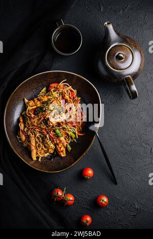 Buckwheat noodle in a black bowl on chicken fillet with tea Stock Photo