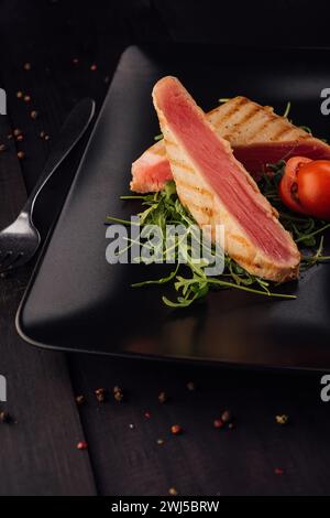 Grilled tuna steak on black plate - soft focus point Stock Photo