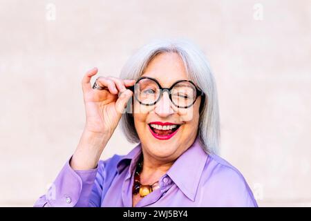senior woman in glasses smiling and winking Stock Photo