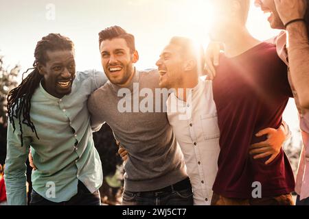 Group of multiracial men laughing together outdoors - Expression of joy and friendship among diverse friends. Stock Photo